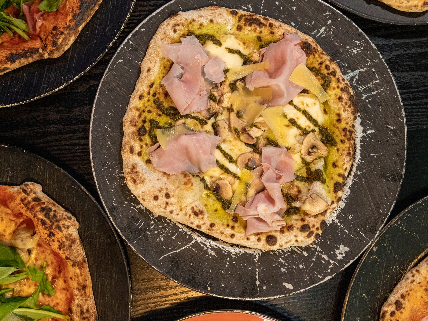 Cuatro pizzas de masa madre distintas sobre la mesa de trabajo