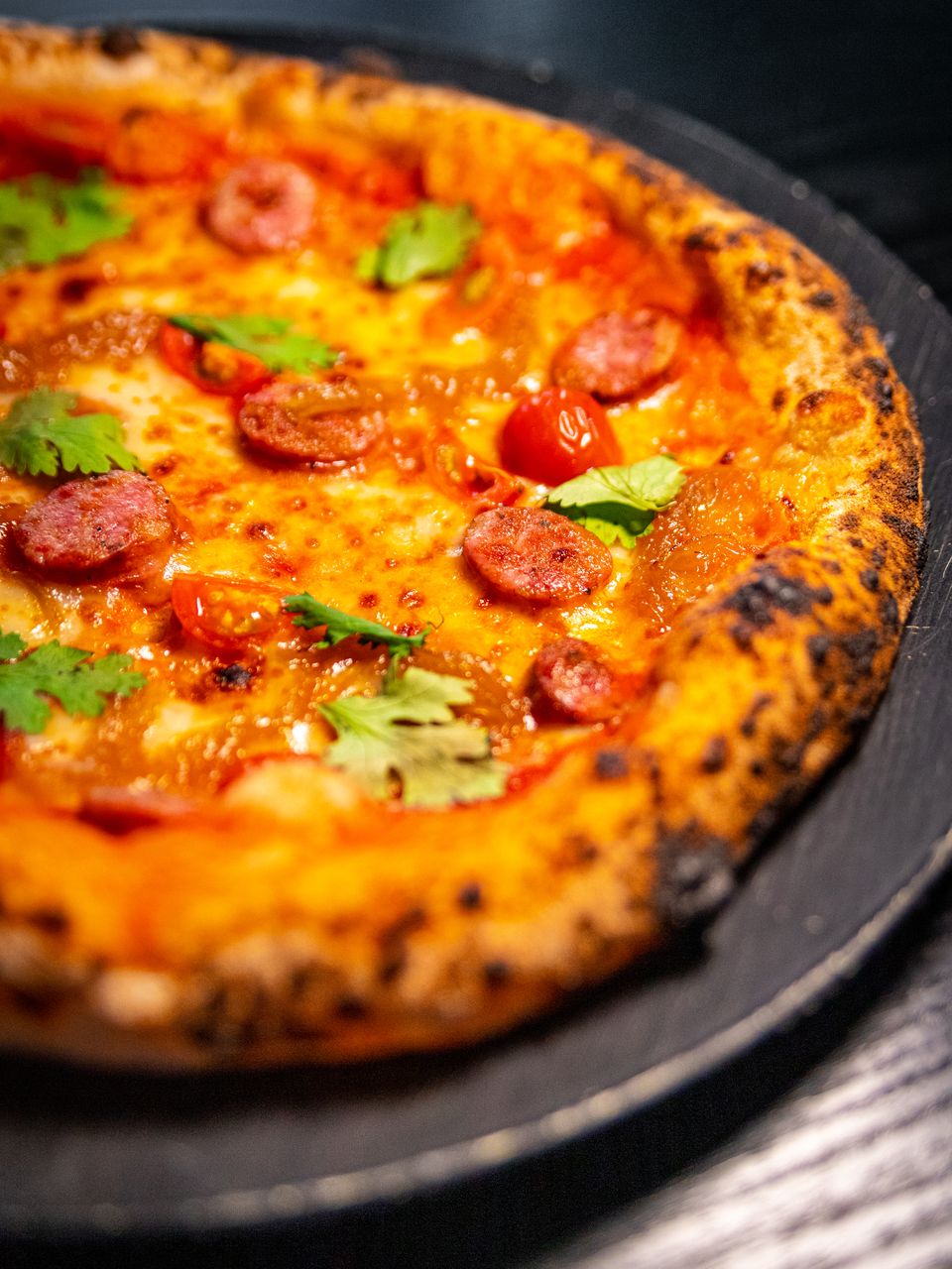 Pizza de chorizo y tomate de masa madre, con rodajas de chorizo y cilantro fresco