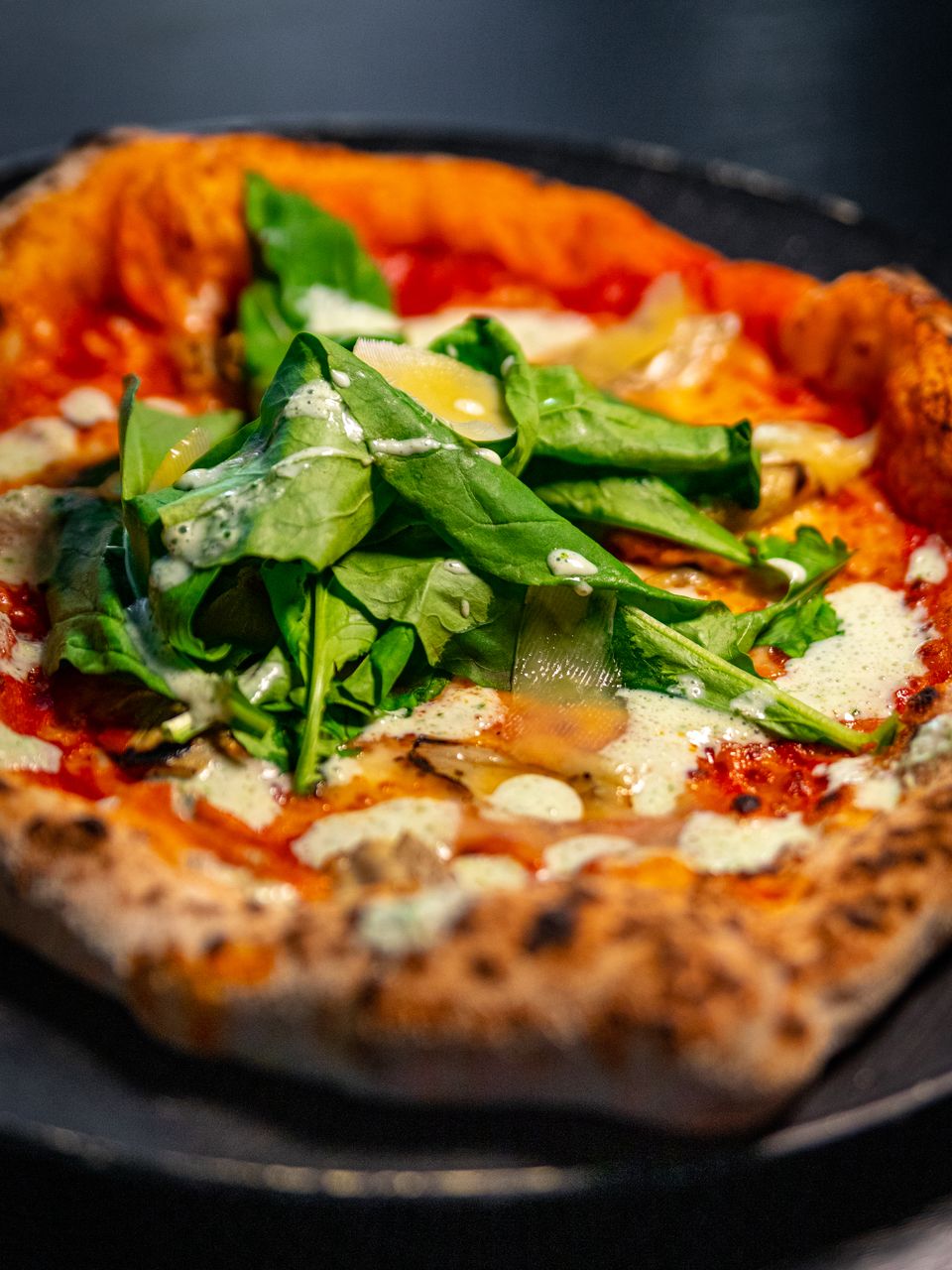 Pizza de espinaca y queso de masa madre, hojas de espinaca fresca sobre queso fundido