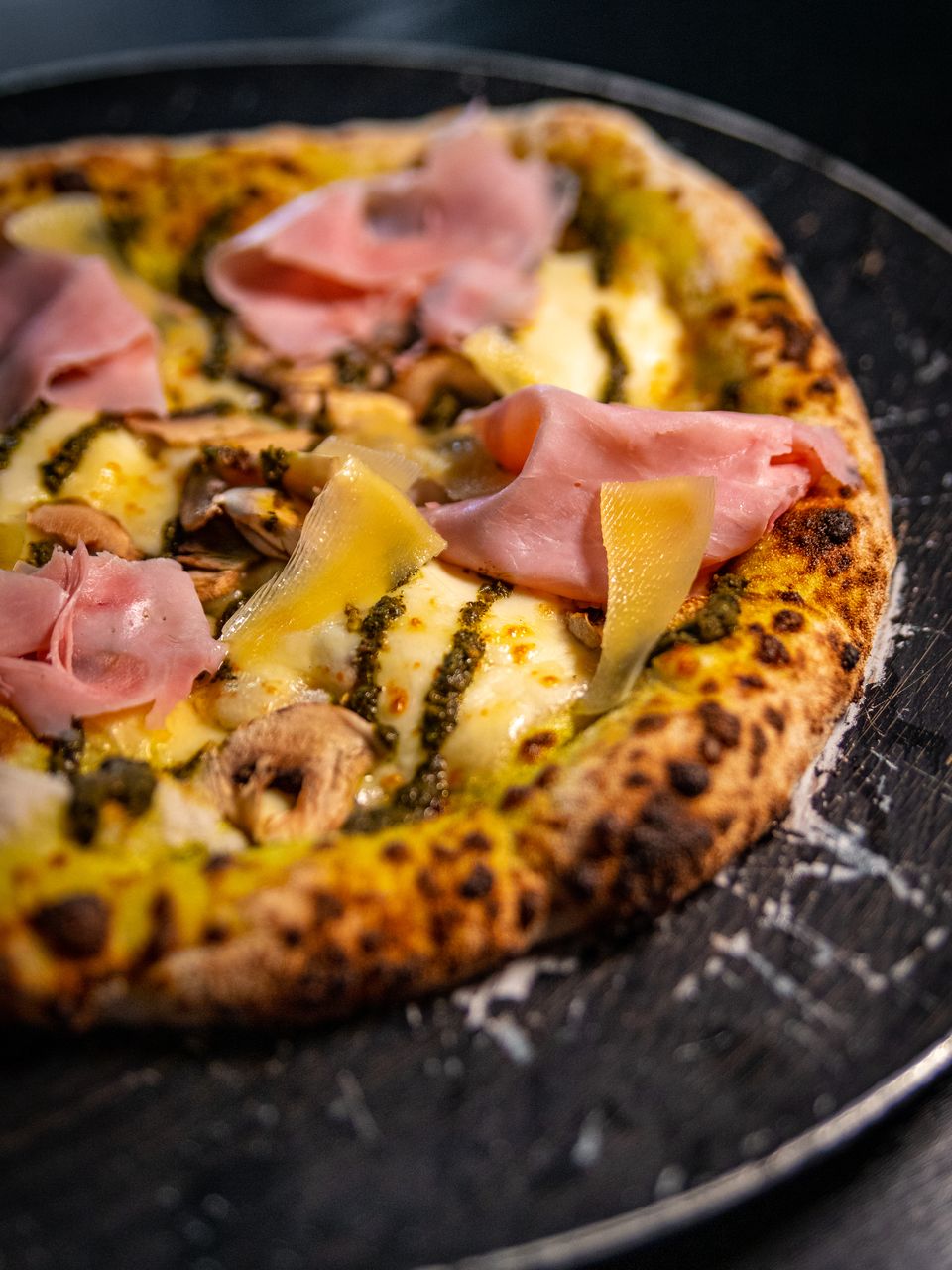 Pizza de jamón, pesto y champiñones de masa madre, con queso derretido y corteza tostada