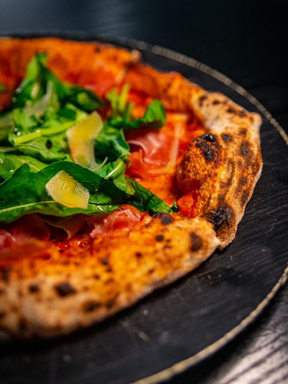Pizza de prosciutto y rúcula de masa madre, con láminas de parmesano